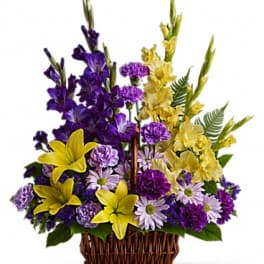 Basket arrangement of purple, yellow, and lavender flowers
