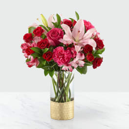 Bouquet of red roses, pink lilies, and carnations in a glass vase