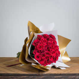 Bouquet of red roses wrapped in gold and white paper