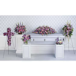 Funeral casket spray with pink and purple flowers on a white casket