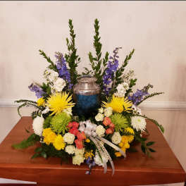 Colorful funeral urn arrangement with yellow, white, pink, and purple flowers