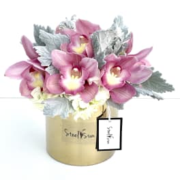 Pink orchids arranged in a gold box with silver foliage