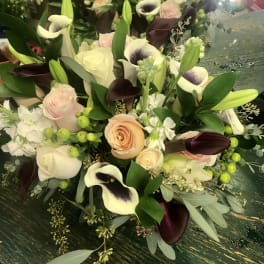 Bouquet of cream roses, calla lilies, and dark purple tulips