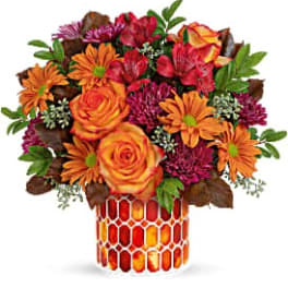 Orange roses and daisies in a patterned vase