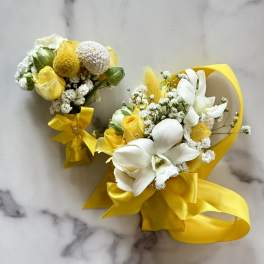 Yellow and white floral bouquets with ribbon bows on a marble surface