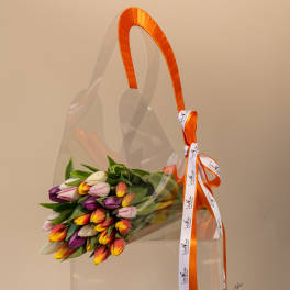 Bouquet of multicolored tulips in clear wrap with an orange ribbon