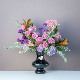 Pink and purple floral arrangement in a black vase