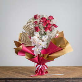 Bouquet of red roses and white orchids wrapped in pink and gold paper