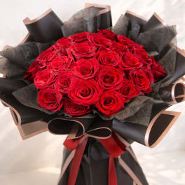 Bouquet of red roses wrapped in black paper with red ribbon