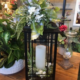 Black lantern with white candle and white floral accents