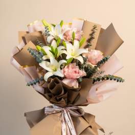Bouquet of white lilies and pale pink roses wrapped in brown and blush paper