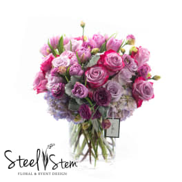 Pink and purple bouquet of roses and tulips in a clear glass vase