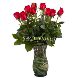 Red roses arranged in a clear glass vase with greenery