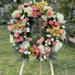 Large floral wreath with pink roses, white hydrangeas, and yellow orchids on an easel