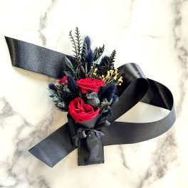 Small bouquet of red roses with black ribbon on a marble surface