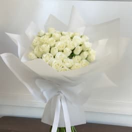 Bouquet of white roses wrapped in white paper with a ribbon