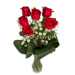 Bouquet of red roses and small white daisies in a clear glass vase