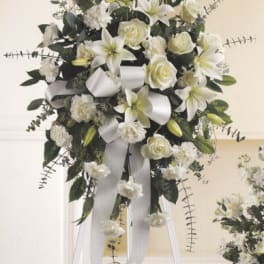 White floral standing spray on an easel with ribbon streamers