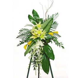 Tall floral standing spray with white lilies, yellow callas, and lush greenery