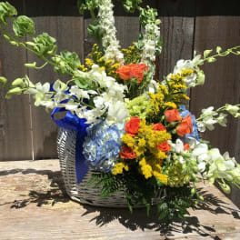 Mixed flower basket with white orchids, orange roses, blue hydrangea, and yellow filler