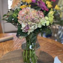 Mixed bouquet with hydrangea, gerbera daisies, and yellow roses in a clear glass vase