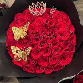 Round bouquet of red roses with a tiara and gold butterfly decorations