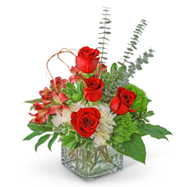Red roses and pink flowers in a clear square vase