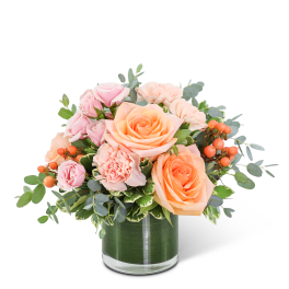 Peach and pink roses with carnations in a glass vase