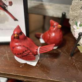 Two red cardinal figurines on a shelf