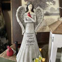 Angel figurine holding a red cardinal with small flowers at the base