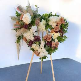 Heart-shaped floral arrangement on an easel with roses and greenery