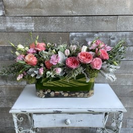 Pink and peach roses arranged in a rectangular glass vase