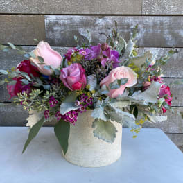 Pink and purple roses arranged in a white vase
