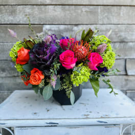 Colorful mixed bouquet in a black container with roses and bright green blooms