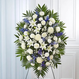 Standing funeral spray of white and blue flowers on an easel