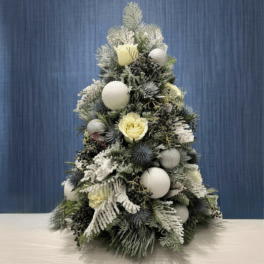 Snow-dusted Christmas tree arrangement with pale yellow roses and white ornaments