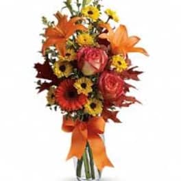 Bouquet of orange lilies, pink roses, and yellow daisies in a glass vase