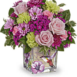 Pink and purple bouquet in a square glass vase with a bird design