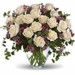 White roses and purple filler flowers in a clear glass vase