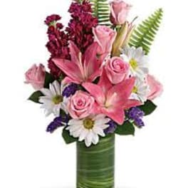 Pink lilies and roses in a green vase with white daisies