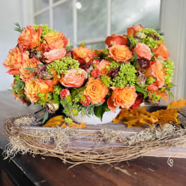 Orange and pink rose arrangement in a white basket on a table
