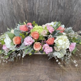 Low floral arrangement with pink, peach, and white blooms