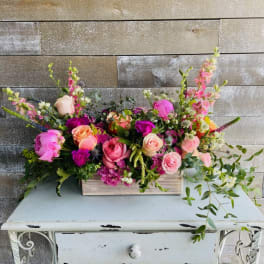 Long floral arrangement with pink and peach roses in a wooden box