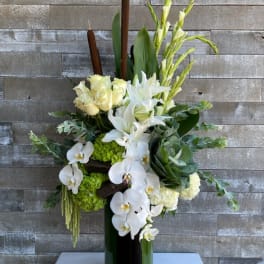 White orchids, lilies, and roses arranged in a tall vase
