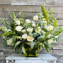 White roses and pale blooms arranged in a square glass vase