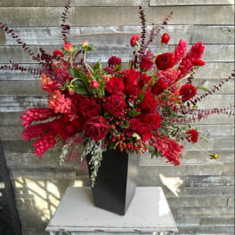Large red floral arrangement in a tall black vase