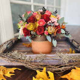 Bouquet of red, pink, and yellow roses in a copper-toned vase