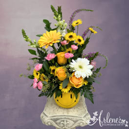Mixed yellow, pink, and white flowers in a smiley-face pot
