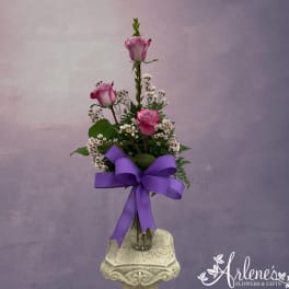 Pink roses in a glass vase with a purple ribbon