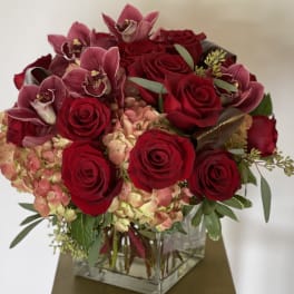 Red roses and pink orchids in a square glass vase